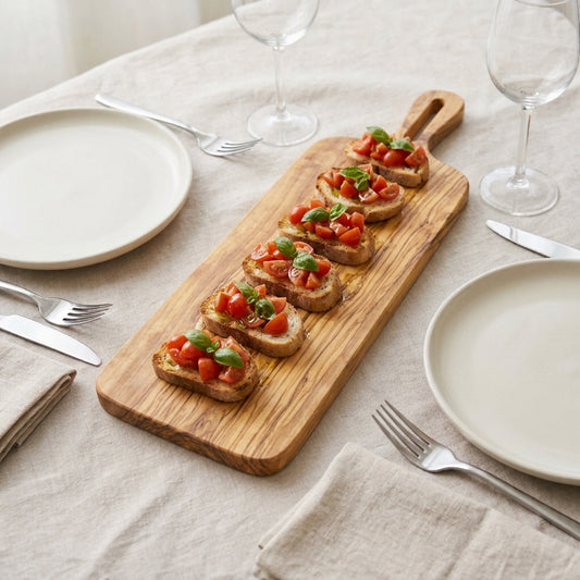Long olive wood serving board with tomato bruschetta on a laid linen table