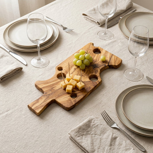 Cheese-shaped olive wood board with cheese cubes and grapes on a laid linen table