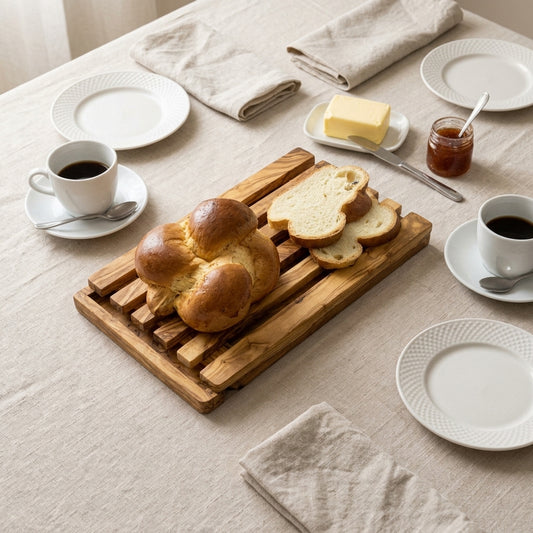 Olive wood bread board with crumb grid and a sliced brioche at a breakfast table