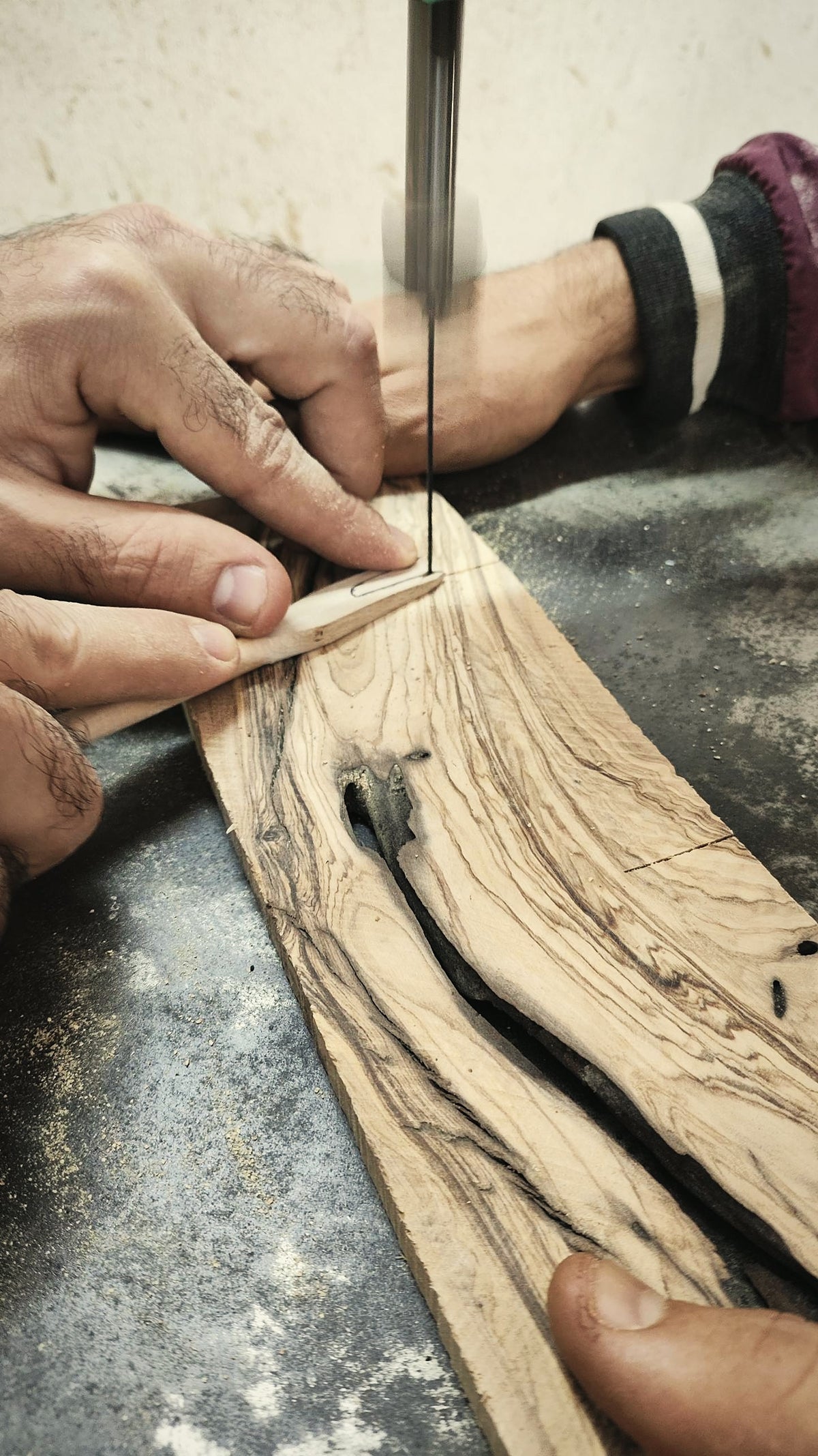 Artisan cutting an olive wood board by hand on a band saw