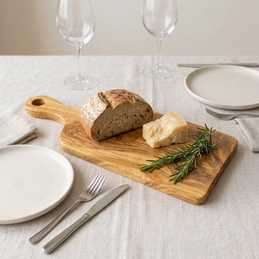 Olive wood paddle board with handle on a set table, with country bread, cheese and rosemary